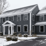 Snowy two-story blue house with white trim and a front porch.