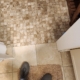 Shower - J.E.P. Contracting | J.E.P. Contracting Top-down view of a person standing on a beige bath mat in a tiled bathroom, wearing gray sneakers and light shorts beside a wooden stool. | J.E.P. Contracting